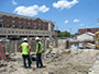 Construction site, July 8, 2014. 2 construction workers looking at third wall of foundation.