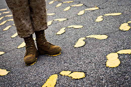 soldier standing on yellow footprints painted on asphalt